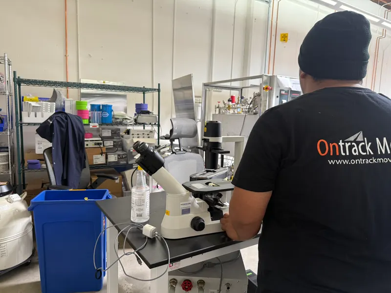 Ontrack Moving crew member standing beside an inverted microscope on a lab bench during the Wild Type Foods relocation in San Francisco