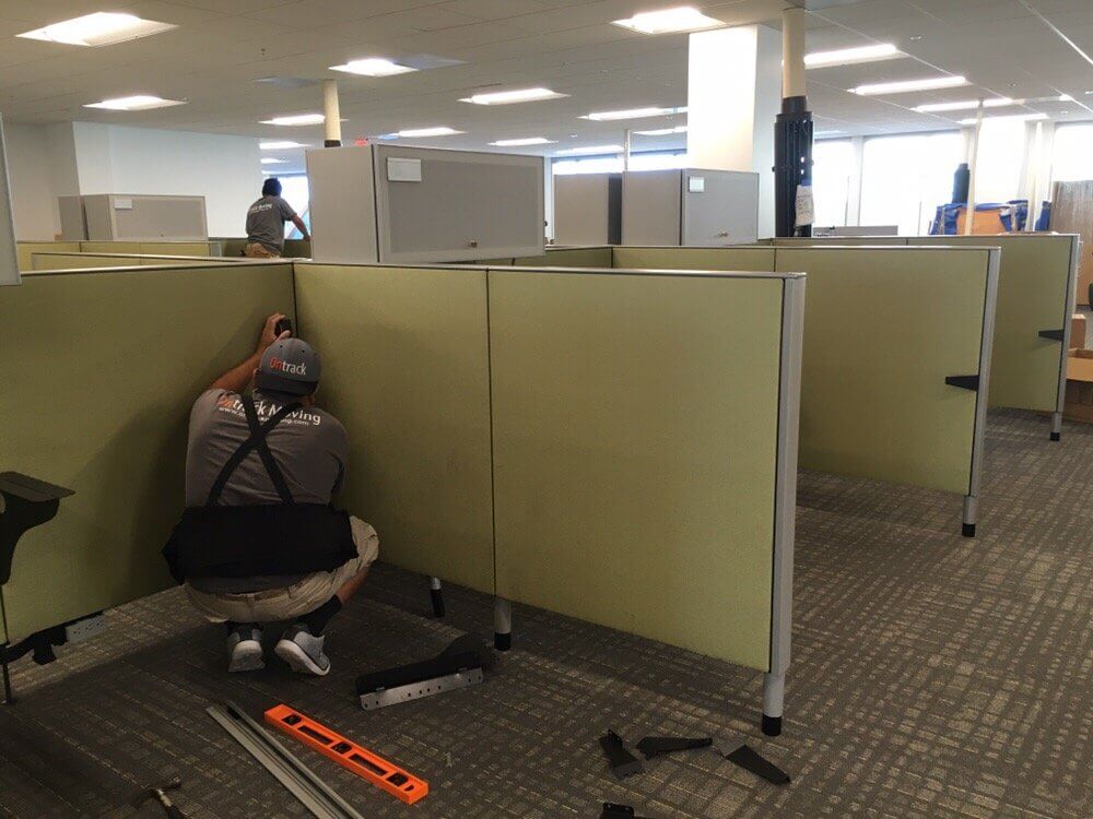 Ontrack Moving crew member working on cubicle panel workstations in an open-plan office