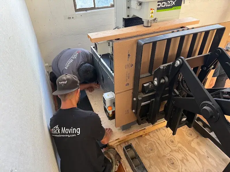 Ontrack Moving crew securing a palletized Tormach 1100MX CNC mill with lumber braced across the machine