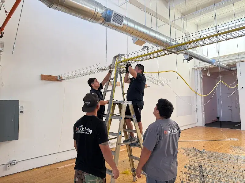 Ontrack Moving crew removing a ceiling-suspended cable tray before a CNC machine move in San Francisco