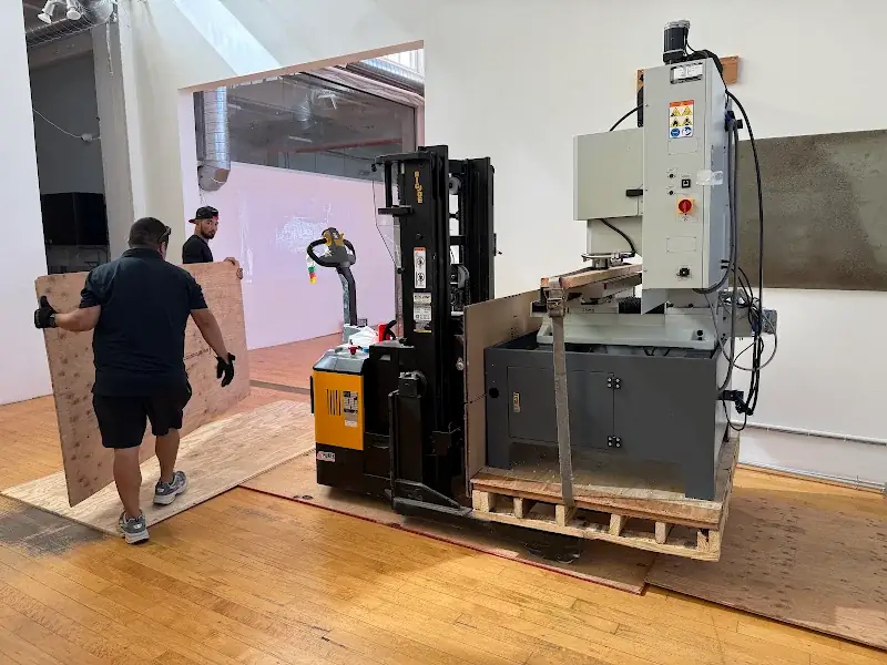 Lift carrying a palletized Tormach 1100MX CNC mill over plywood floor protection during a San Francisco to Emeryville machinery move