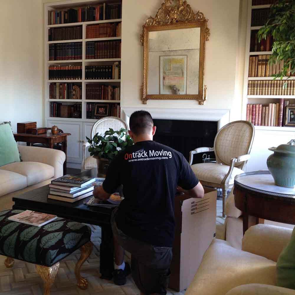 Ontrack Moving packer boxing books from built-in shelves in a Bay Area living room during a full service packing job