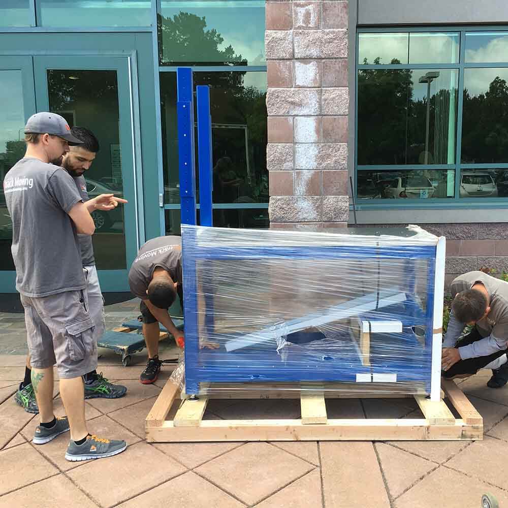 Ontrack Moving crew crating analytical lab equipment on a wooden pallet with protective wrap for a Sunnyvale research facility